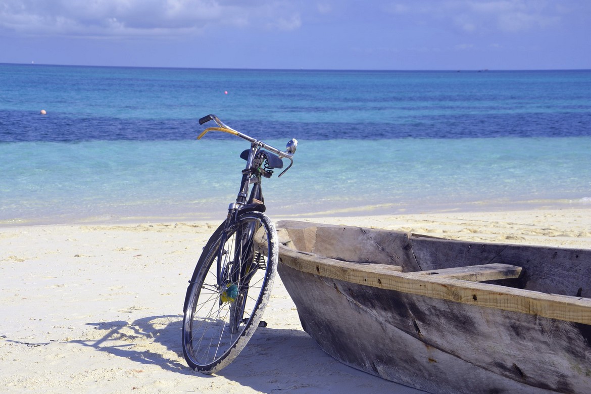 Bicycle and wooden boat resting on the sandy shores of Gold Zanzibar