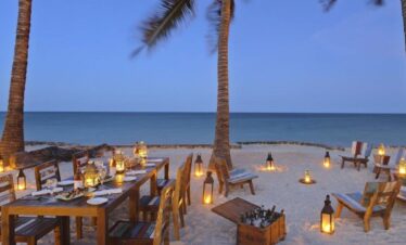 Bluebay Beach Resort candlelit beachside dining under palm trees at dusk