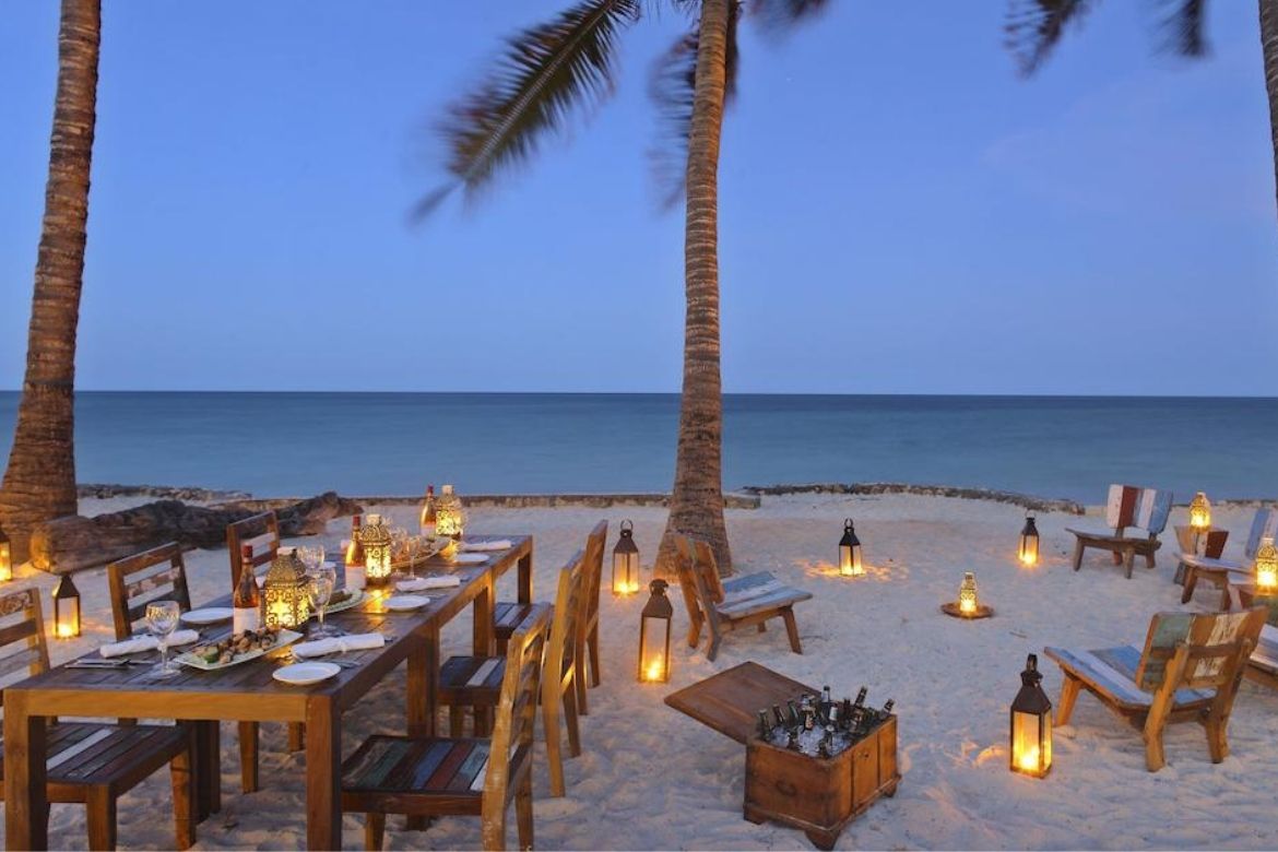Bluebay Beach Resort candlelit beachside dining under palm trees at dusk