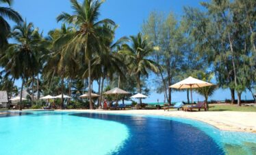 Bluebay Beach Resort infinity pool with sun loungers and swaying palm trees