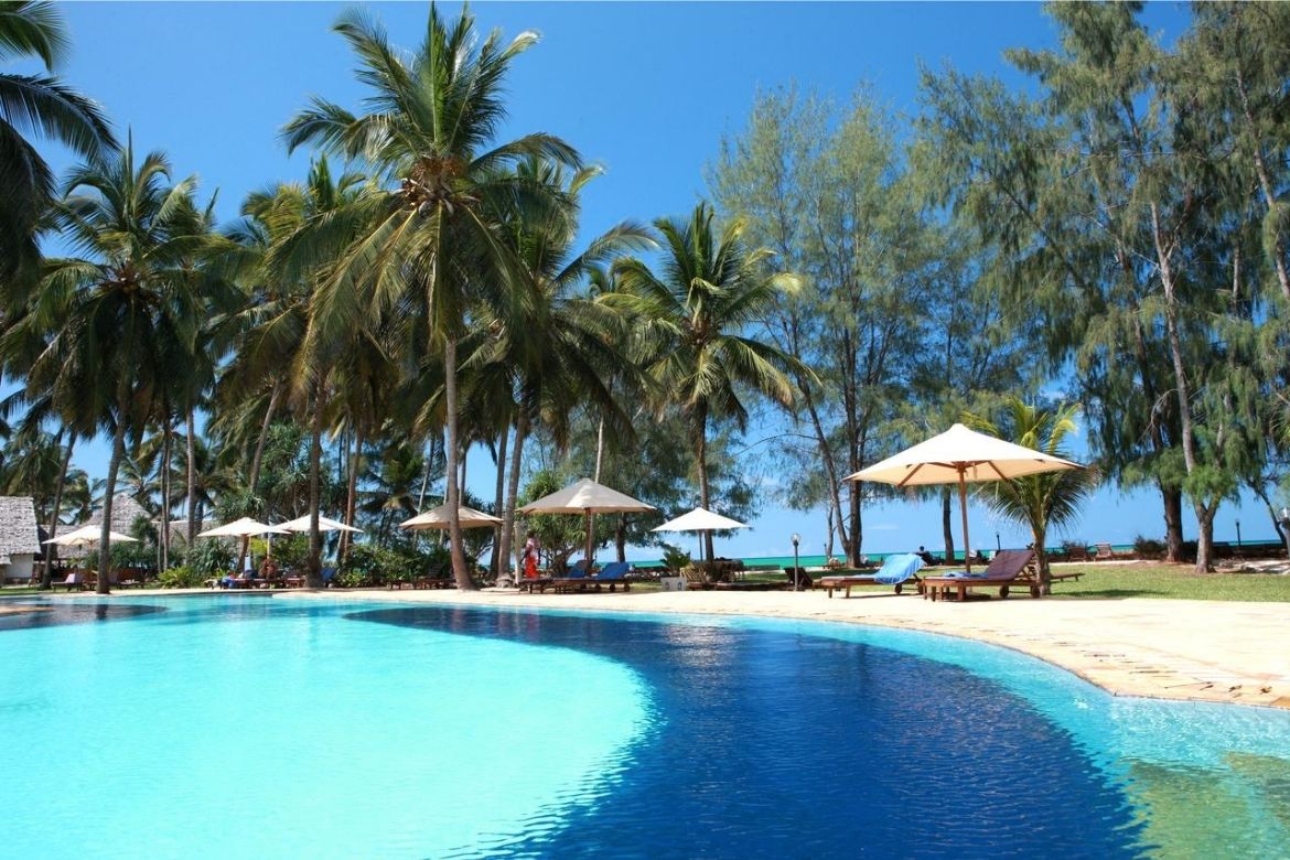 Bluebay Beach Resort infinity pool with sun loungers and swaying palm trees