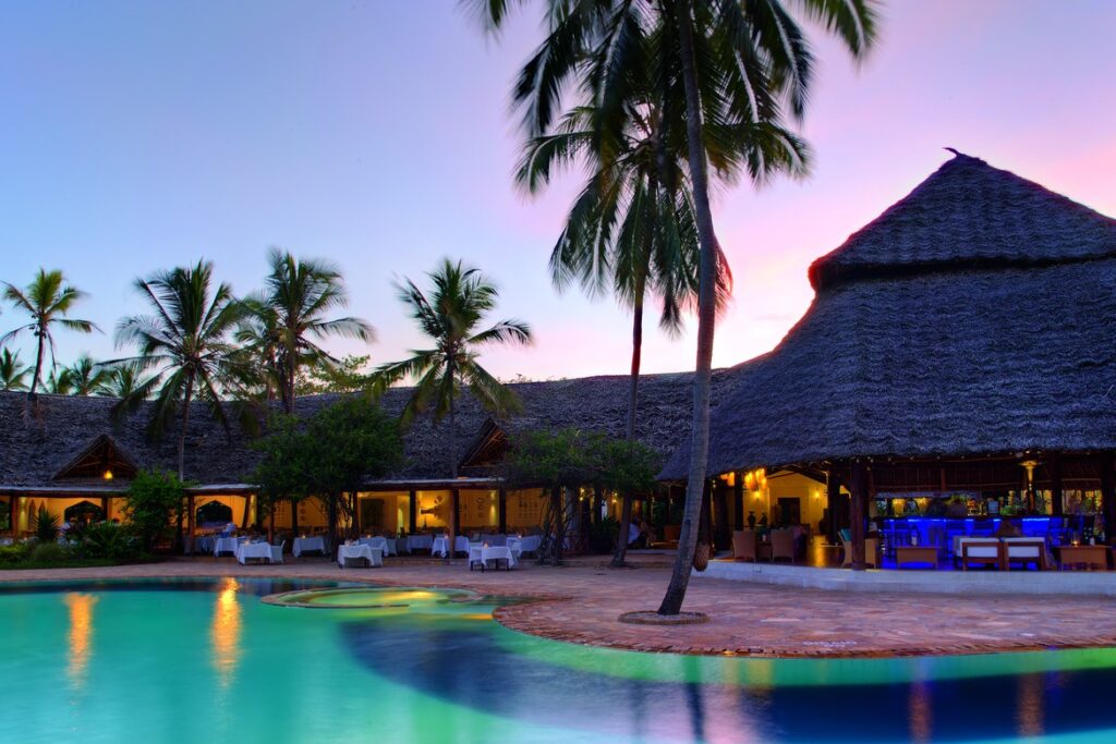 Bluebay Beach Resort poolside with thatched-roof bar and tropical palm trees