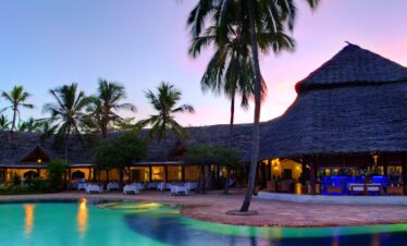 Bluebay Beach Resort poolside with thatched-roof bar and tropical palm trees