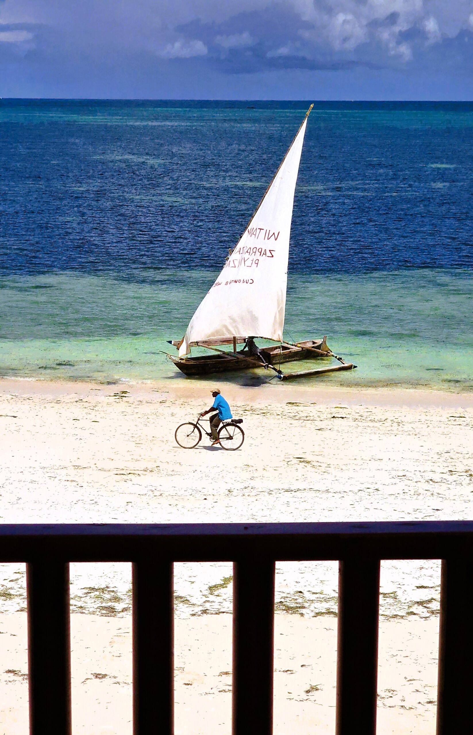 Dream of Zanzibar beachfront with dhow and cyclist