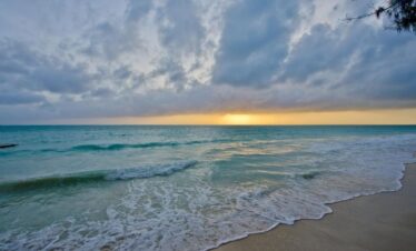 Golden sunset over the ocean at Bluebay Beach Resort with gentle rolling waves