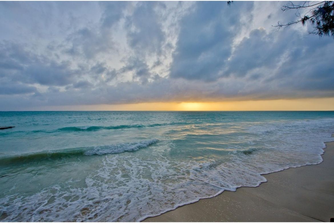 Golden sunset over the ocean at Bluebay Beach Resort with gentle rolling waves