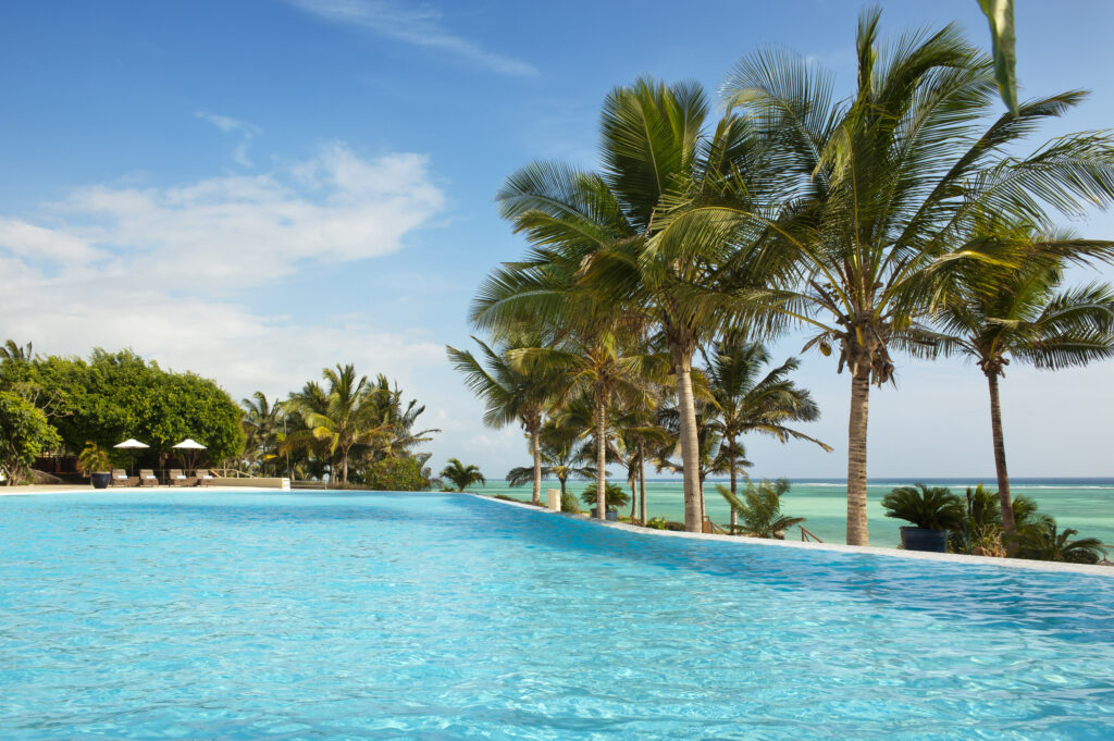 Infinity pool at Melia Zanzibar lined with palm trees and sun loungers