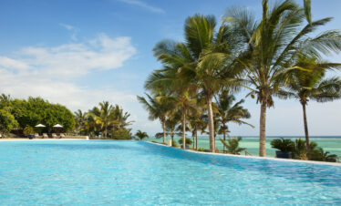 Infinity pool at Melia Zanzibar lined with palm trees and sun loungers