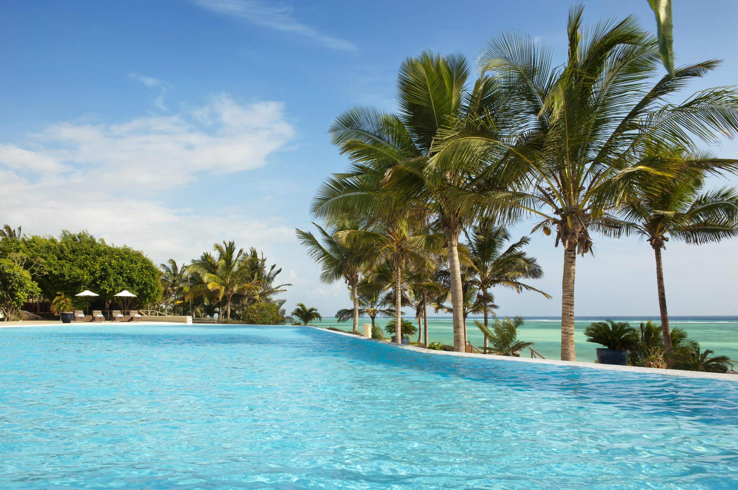 Infinity pool at Melia Zanzibar lined with palm trees and sun loungers