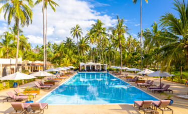 Large outdoor swimming pool surrounded by palm trees and sun loungers at Tui Blue Bahari