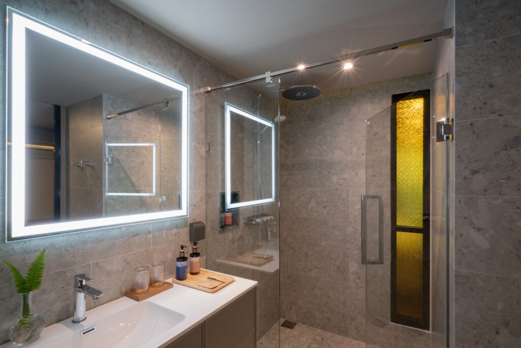 Modern bathroom with illuminated mirror and glass shower enclosure at La Flora Khao Lak