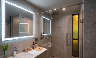 Modern bathroom with illuminated mirror and glass shower enclosure at La Flora Khao Lak