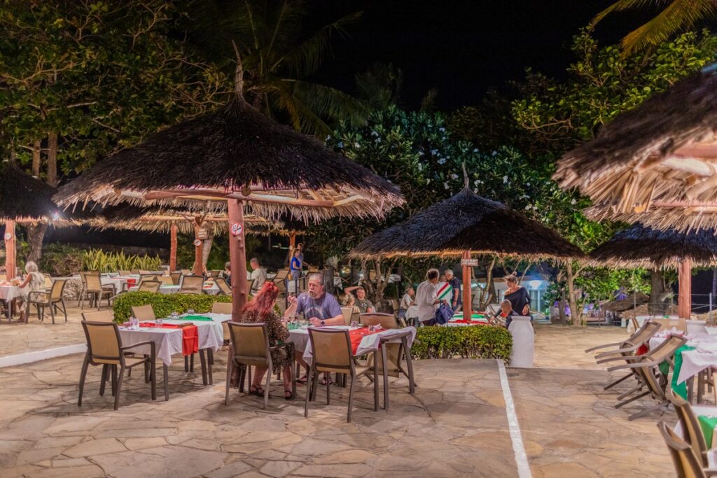 Outdoor dining at Karafuu Beach Resort under thatched umbrellas at night
