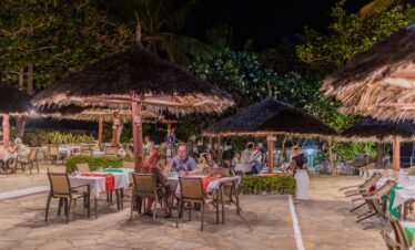Outdoor dining at Karafuu Beach Resort under thatched umbrellas at night