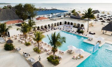 Poolside dining area with palm trees and ocean view at Gold Zanzibar resort