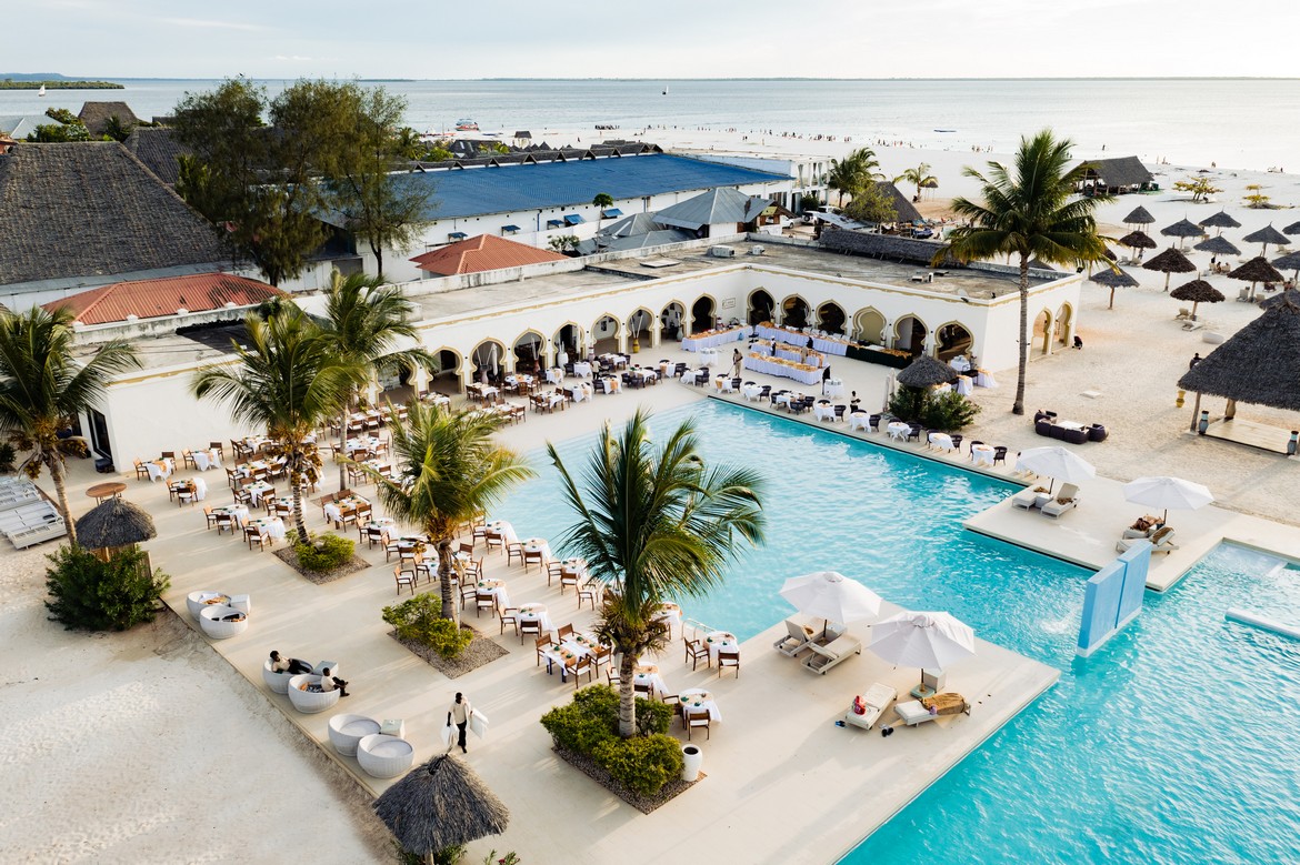 Poolside dining area with palm trees and ocean view at Gold Zanzibar resort