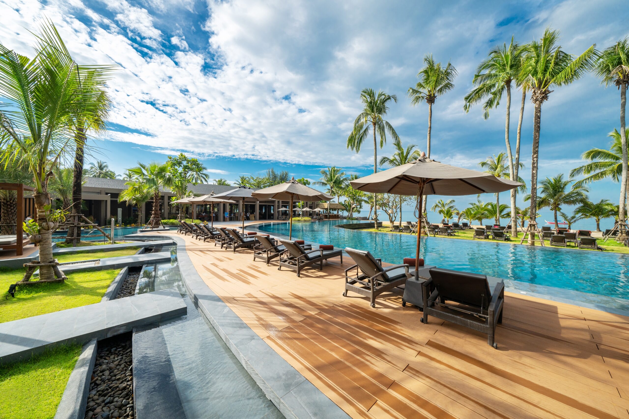 Relaxing pool area with sun loungers under palm trees at La Flora Khao Lak