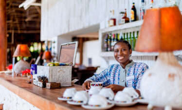 Smiling bartender at Diamonds Mapenzi Beach Resort serving drinks at the bar