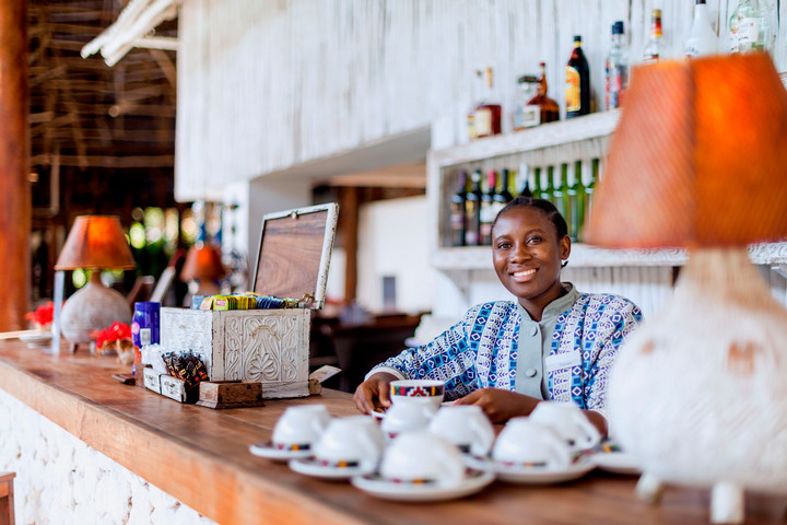 Smiling bartender at Diamonds Mapenzi Beach Resort serving drinks at the bar