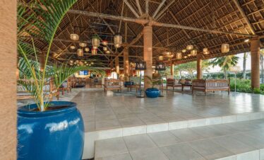 Spacious open air lobby with high thatched roof and traditional seating at Tui Blue Bahari