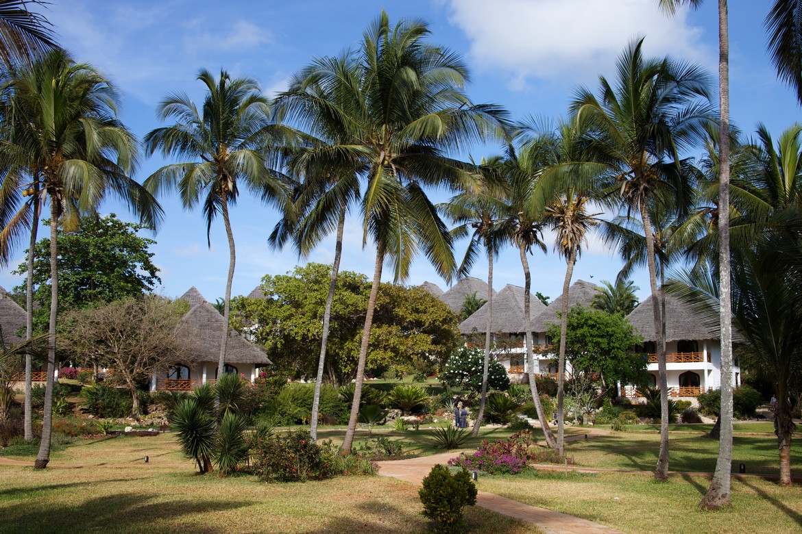 Thatched roof villas at Bluebay Beach Resort surrounded by lush tropical gardens