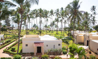 View of lush gardens with palm trees leading to the ocean at Tui Blue Bahari resort